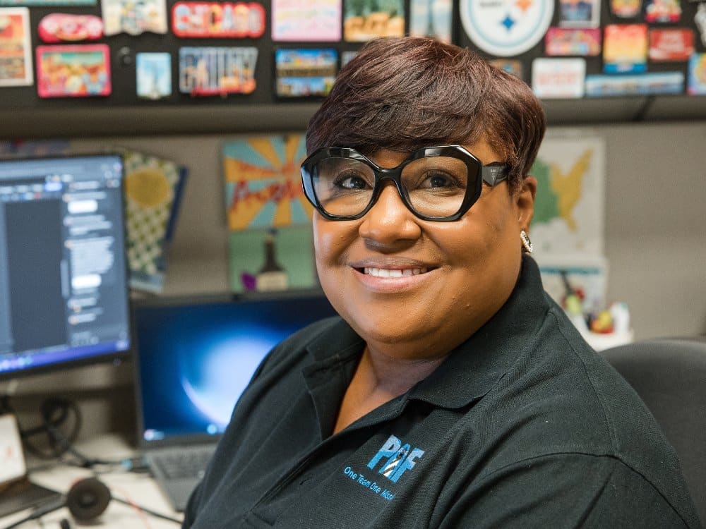 Smiling woman at cubicle, part of PAF team