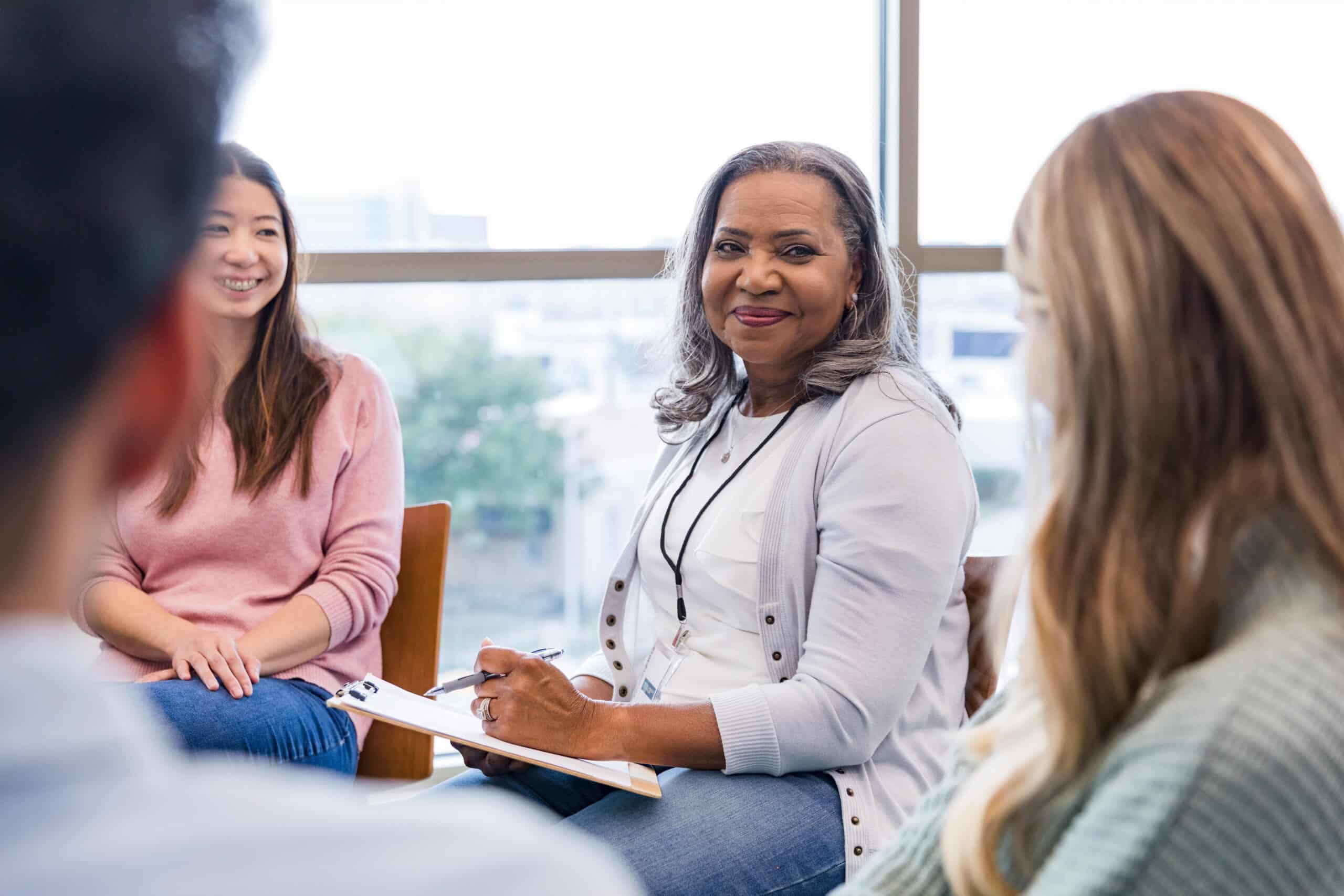 Female counselor smiles at people in support group